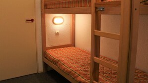 Une chambre avec un lit superposé, un lit simple et une échelle.