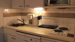 Une cuisine équipée d’un lave-vaisselle Bosch, d’une machine à café, d’un four à micro-ondes et d’une cuisinière.