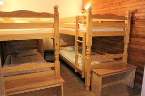 A bunk bed room with wooden furniture and a wooden wall.