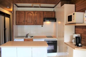 Compact kitchen with microwave, coffee maker, and modern sink.