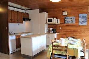 Enjoy meals at the central island with sink, microwave, and coffee maker, and dine at the set table with plates, bowls, and glasses.