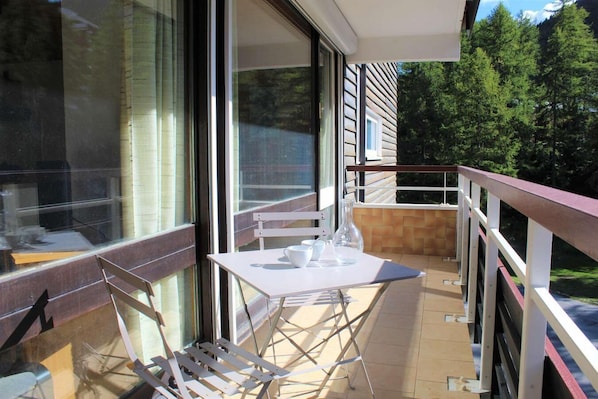 Enjoy a peaceful retreat with a balcony offering a serene forest view and a building in the distance.