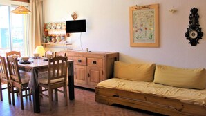 A cozy room with a wooden dining table, chairs, a sofa, a television, and a wall-mounted clock. - Resort center, 3rd floor, balcony, tv, 30m², Vars (Vars)