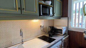A compact kitchen with green cabinets, a white sink, a microwave, a coffee maker, and a dishwasher. - Resort center, 3rd floor, balcony, tv, 30m², Vars (Vars)