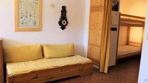 A small room with a wooden sofa, a bunk bed, a wall clock, and a framed botanical illustration. - Resort center, 3rd floor, balcony, tv, 30m², Vars (Vars)