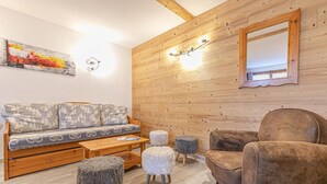 Ein gemütliches Zimmer mit einer Holzwand, einem Sofa, einem Sessel und einem kleinen Tisch.