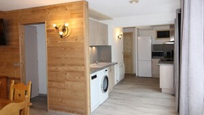 Eine kompakte Küche mit Waschmaschine, Holzwänden und einer Essecke mit Tisch und Stühlen.