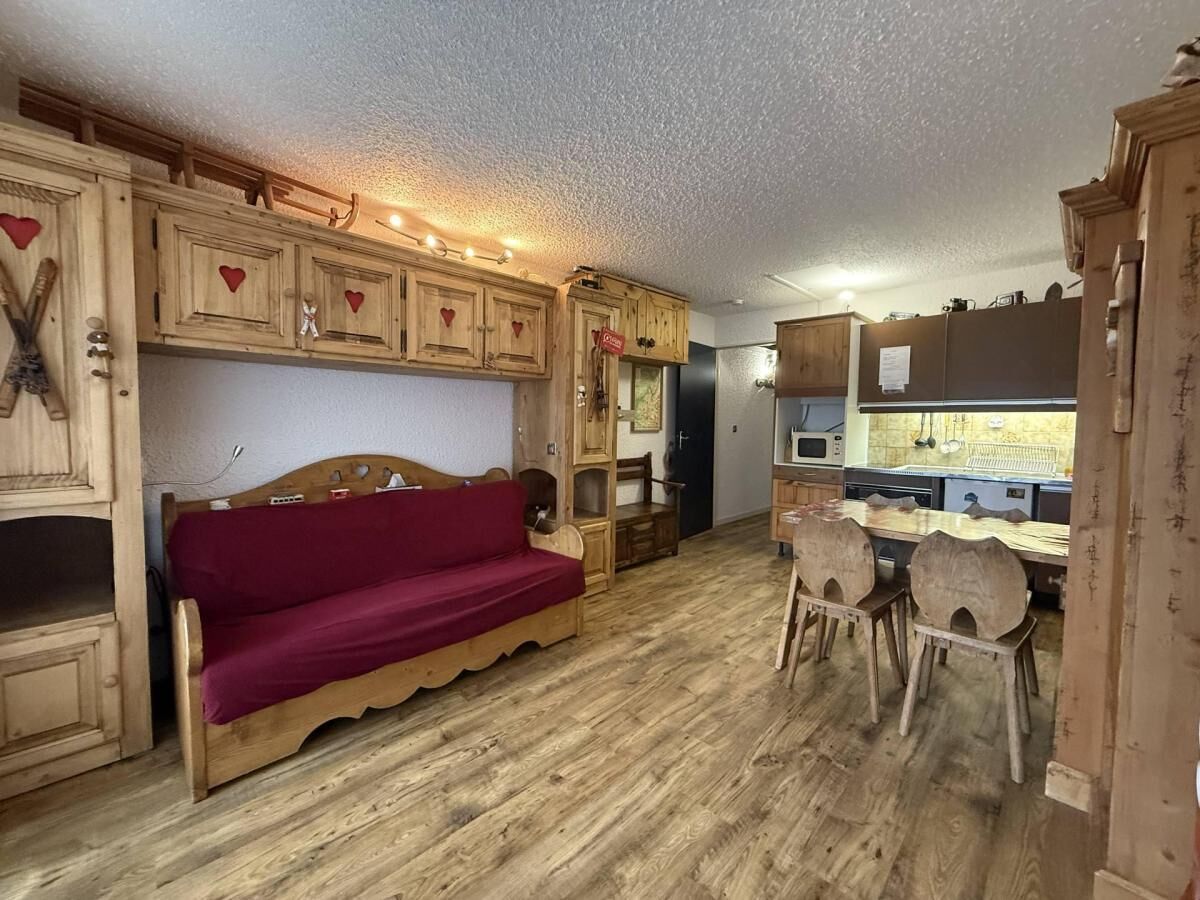A rustic room with wooden furniture, a red sofa, and a dining area with chairs.