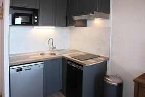 A compact kitchen with a microwave, sink, and dishwasher.