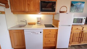 A kitchen with wooden cabinets, a Bosch dishwasher, a coffee maker, and a microwave. - 100m from ski slopes, 2nd floor, view ski slopes/mountain, tv, 60m², Les Saisies (Les Saisies)