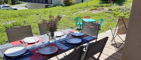 An outdoor dining area with a table set for four, surrounded by chairs.
