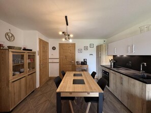 A compact kitchen with a wooden dining table, black chairs, and a black countertop.