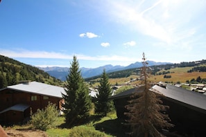 A mountain cabin with a view of a valley and distant mountains.