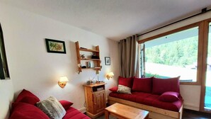 Una sala de estar con sofás rojos, una mesa de centro de madera y un mueble de televisión con una radio.
