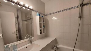 Un baño con lavamanos, espejo y ducha.