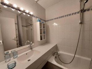 Un bagno con lavandino, specchio e doccia.