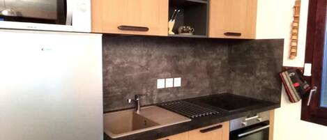 A compact kitchen with a microwave, sink, and oven.