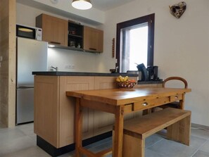 A kitchen with wooden cabinets, a built-in microwave, a fruit basket on the counter, and a window with a view. - 50m from ski slopes, 3rd floor, view valley, balcony, tv, ski locker, 57m², La Plagne (La Plagne)