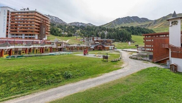 A hotel with multiple buildings, a central courtyard, and a mountainous backdrop. - 5m from ski slopes, 1st floor, view ski slopes, balcony, tv, 21m², La Plagne (La Plagne)