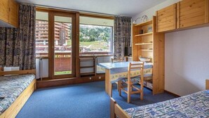 A room with a bunk bed, a desk with a chair, a window with curtains, and wooden shelves. - 5m from ski slopes, 1st floor, view ski slopes, balcony, tv, 21m², La Plagne (La Plagne)