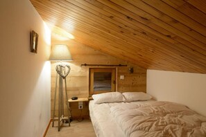 A cozy attic bedroom with a wooden ceiling, a bedside lamp, a heart-shaped decoration, and a bed with white linens. - 150m from ski slopes, 1st floor, balcony, tv, ski locker, 76m², Montchavin La Plagne (Bellentre)