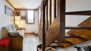 Una habitación acogedora con un banco de madera, un pequeño sofá y una ventana con cortinas.