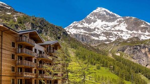A wooden lodge with balconies overlooking a mountainous landscape with a snow-capped peak. - 50m from ski slopes, 6th floor, swimming pool, sauna, hammam, balcony, tv, ski locker, 127m², Tignes (Tignes)