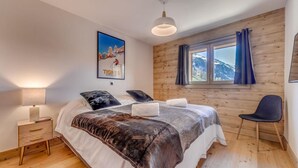A bedroom with a wooden wall, a bed with a mountain view, a desk, and a chair. - 50m from ski slopes, 6th floor, swimming pool, sauna, hammam, balcony, tv, ski locker, 127m², Tignes (Tignes)