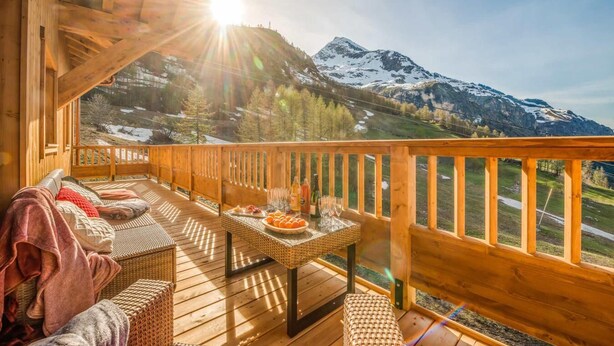 A wooden deck with a table set for dining, overlooking a mountainous landscape with snow-capped peaks. - 50m from ski slopes, 6th floor, swimming pool, sauna, hammam, balcony, tv, ski locker, 127m², Tignes (Tignes)