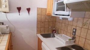 Kompakti keittiö, jossa on mikroaaltouuni, leivänpaahdin, pesuallas ja liesi.