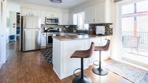 A modern kitchen with white cabinets, a granite countertop, a stainless steel refrigerator, a microwave, and a sink. - The View on Lake Lanier lake view & dock. (Gainesville)