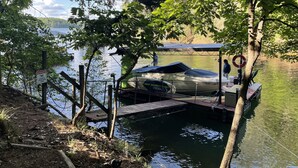 A dock with boats, a warning sign, and a wooden walkway leading to the water. - The View on Lake Lanier lake view & dock. (Gainesville)
