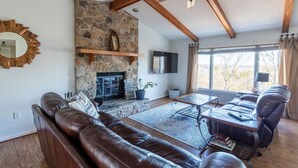 A living room with a stone fireplace, leather sofa, and a ceiling fan. - The View on Lake Lanier lake view & dock. (Gainesville)