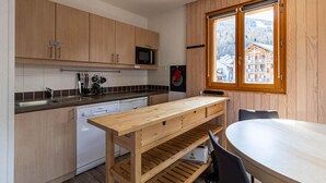 A modern kitchen with wooden cabinets, a microwave, and a large window with a view of a building and mountains.