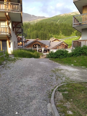 Eine rustikale Berghütte mit Holzhäuschen und einer Schotterauffahrt zu einer Holzterrasse.