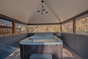 A hot tub in a covered outdoor area with a ceiling light fixture above it.