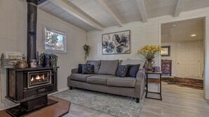 A cozy living room with a fireplace, a grey sofa, a patterned rug, and a painting on the wall. - Cozy Cottage Getaway  (Payson)