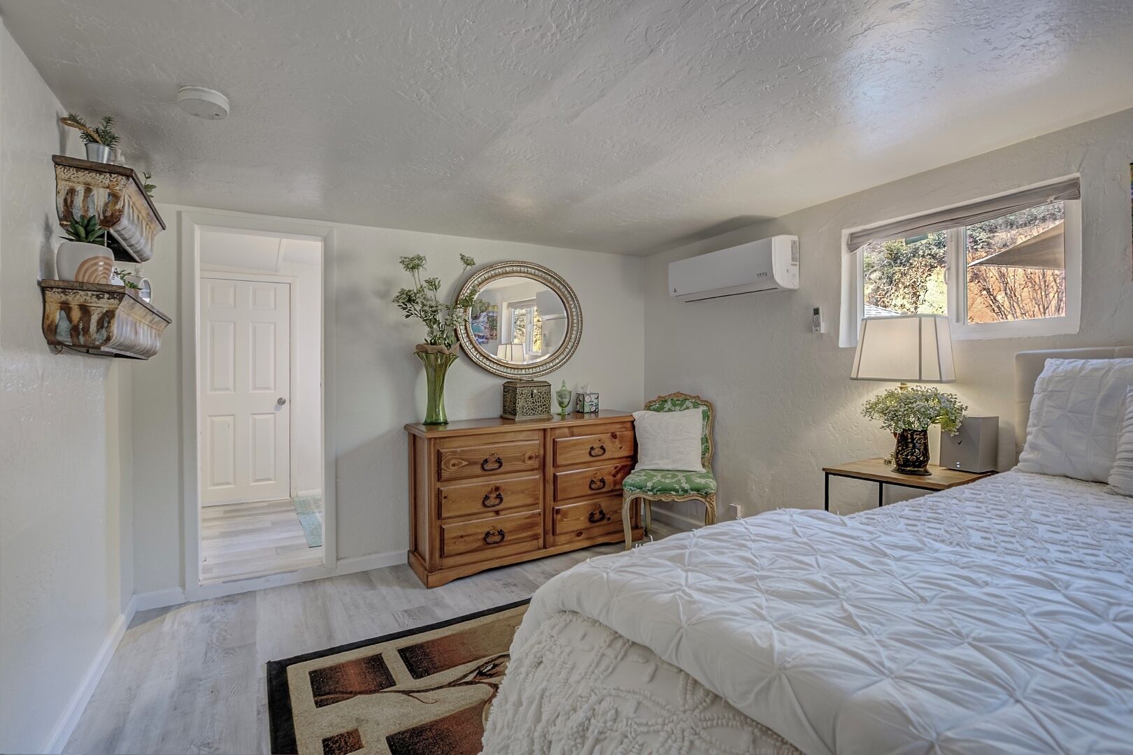 A bedroom with a bed, dresser, chair, and a mirror.