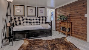 A bedroom with a bed, a standing lamp, a wooden dresser, and a large rug. - Cozy Cottage Getaway  (Payson)