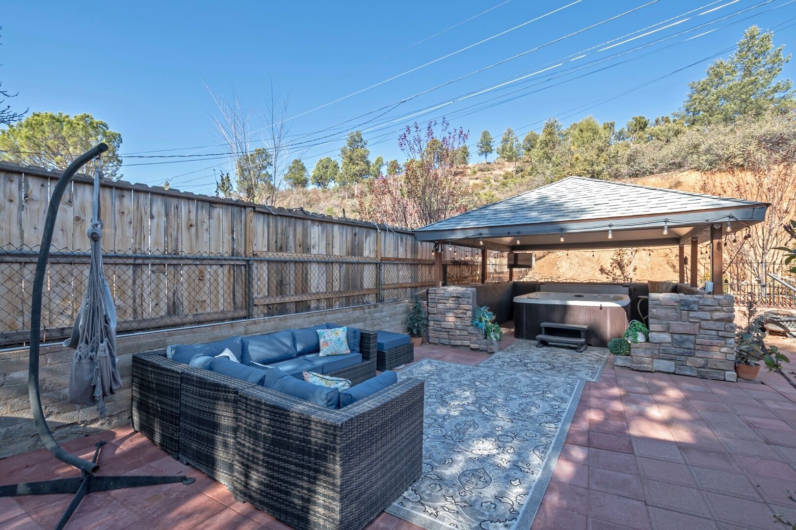 A backyard with a hot tub, outdoor seating, and a pergola.