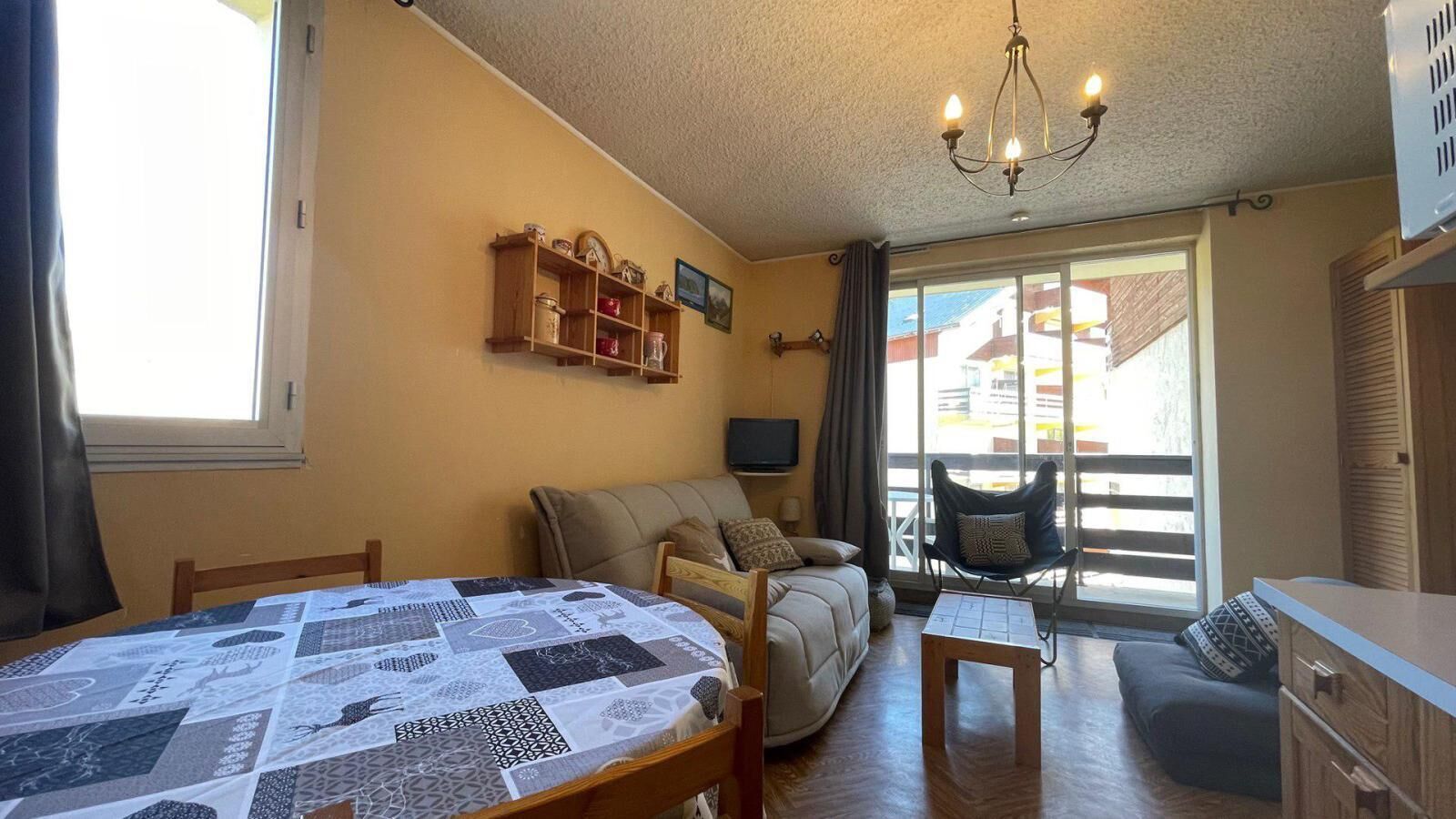 Un salon confortable avec un canapé, une table à manger et un téléviseur. Il y a un balcon avec vue sur les immeubles.