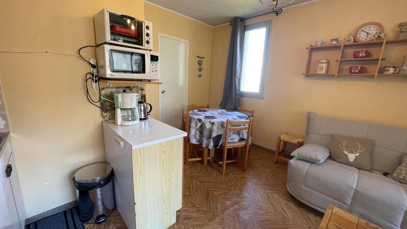 Een knus woongedeelte met een kitchenette, een eettafel en een bank.