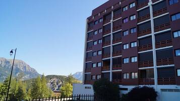 Un immeuble à plusieurs étages doté d’une architecture moderne, caractérisé par une série de balcons et de grandes fenêtres.