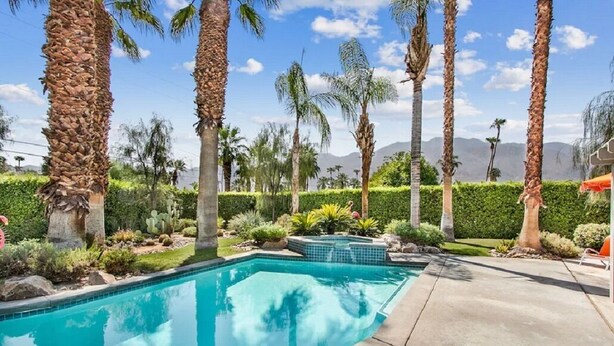 A swimming pool surrounded by palm trees and a landscaped garden.