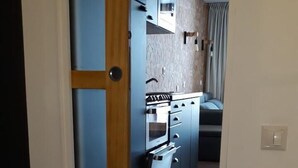Un pasillo estrecho con una zona de cocina que incluye estufa, horno y microondas.