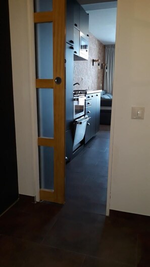 A narrow hallway with a kitchen area featuring a stove, oven, and microwave. - 10m from ski slopes, 2nd floor, balcony, tv, 22m², Les Arcs (Les Arcs)