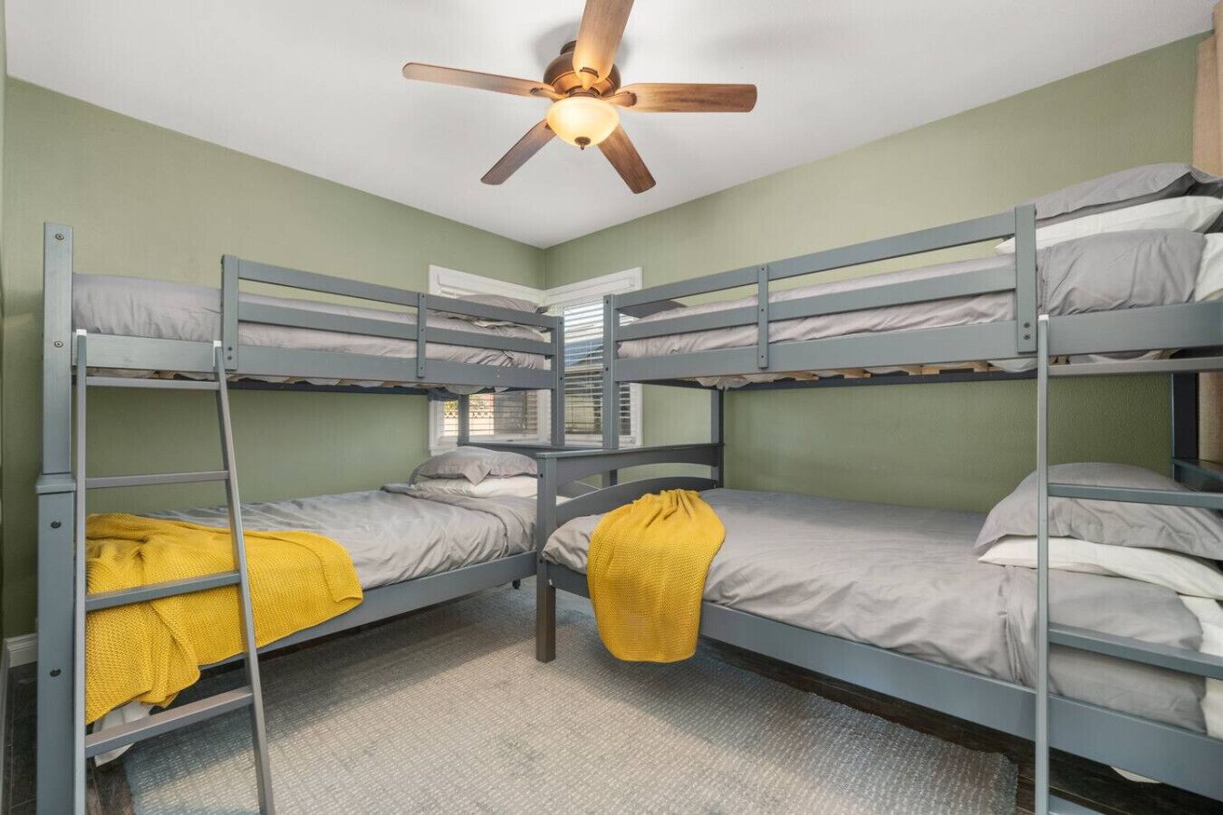 Ein Schlafsaalzimmer mit Etagenbetten, Deckenventilator und Fenster.