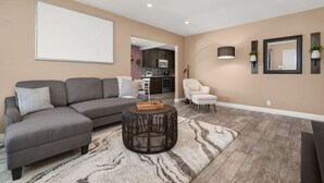 Ein modernes Wohnzimmer mit einem grauen Modulsofa, einem runden Couchtisch und einem gemusterten Teppich.
