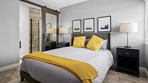 Ein modernes Schlafzimmer mit einem Bett, Nachttischen, einem Spiegel und gerahmten Bildern an der Wand.