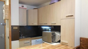 A compact kitchen with wooden cabinets, a toaster, a sink, and a dishwasher. - 50m from resort center, 2nd floor, balcony, tv, ski locker, 26m², Montchavin La Plagne (Bellentre)